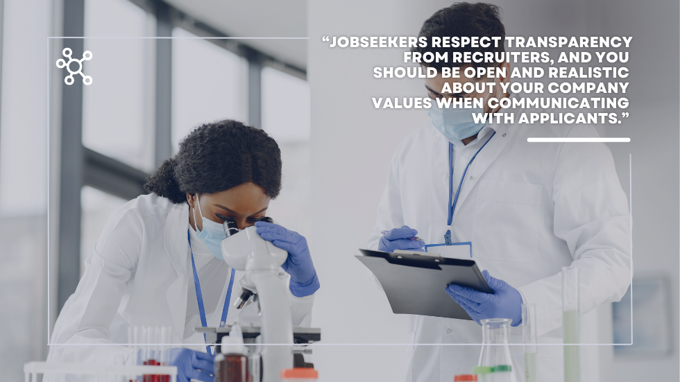 Scientist looking through microscope while another takes notes